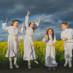 Cztery dzieci w strojach komunijnych skaczą radośnie na tle kwitnącego rzepaku. Zastanawiasz się, ile bierze fotograf za komunie?