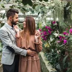 Zakochana para w otoczeniu kwitnących orchidei. Zastanawiasz się, ile kosztuje sesja u fotografa?