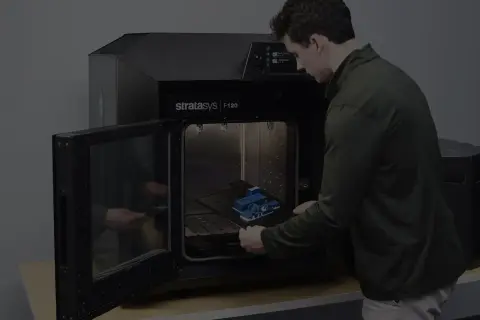 Mężczyzna wkłada wydrukowany model do drukarki 3D Stratasys F120.