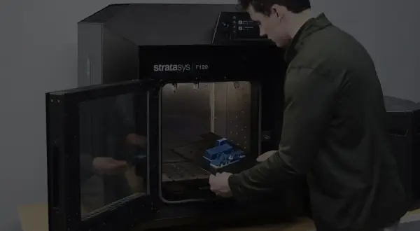 Mężczyzna wkłada wydrukowany model do drukarki 3D Stratasys F120.