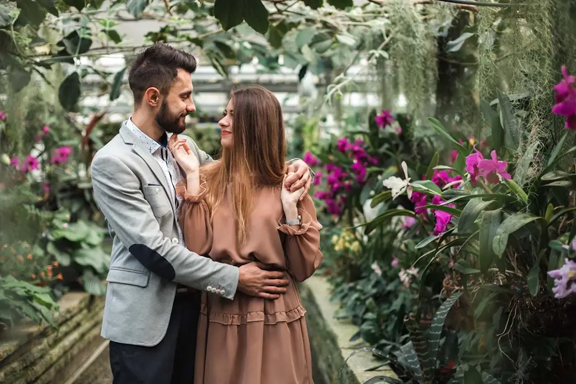 Zakochana para w otoczeniu kwitnących orchidei. Zastanawiasz się, ile kosztuje sesja u fotografa?