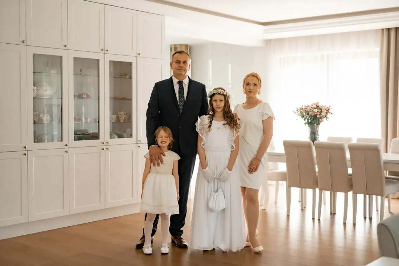 Rodzina w białych strojach na tle nowoczesnej kuchni. Zastanawiasz się, ile bierze fotograf za komunie?