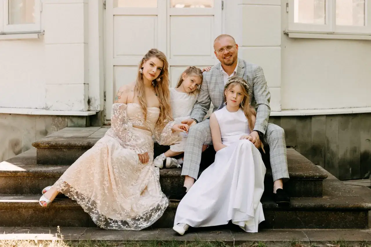 Rodzina na schodach przed domem. Mama w koronkowej sukni, tata w garniturze, dwie córki w białych sukienkach. Zastanawiasz się, ile bierze fotograf za komunie?