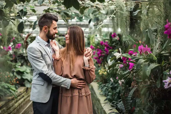 Zakochana para w otoczeniu kwitnących orchidei. Zastanawiasz się, ile kosztuje sesja u fotografa?